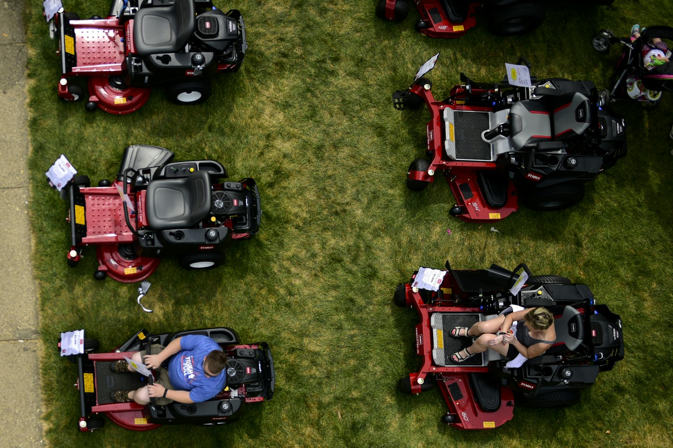 Fairgoers sat in lawnmowers on display at the Minnesota State Fair.