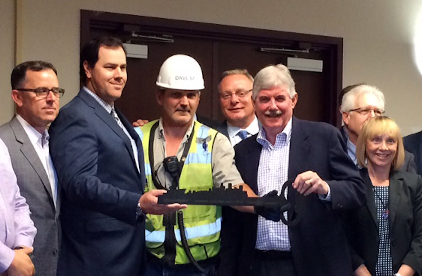 The key to the Vikings stadium is officially turned over to the state in a ceremonial handoff that included, left to right, Vikings chief marketing officer Steve LaCroix, Eric Grenz, Mortenson Construction executive, Mortenson general superintendent Dave Mansell, Ted Mondale, MSFA exec. dir., John Wood, Mortenson Senior Vice President, and Michele Kelm-Helgen, MSFA chair.