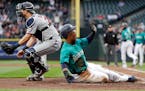 Seattle Mariners' Jean Segura, right, scores as Twins catcher Mitch Garver waits for the throw during the first inning