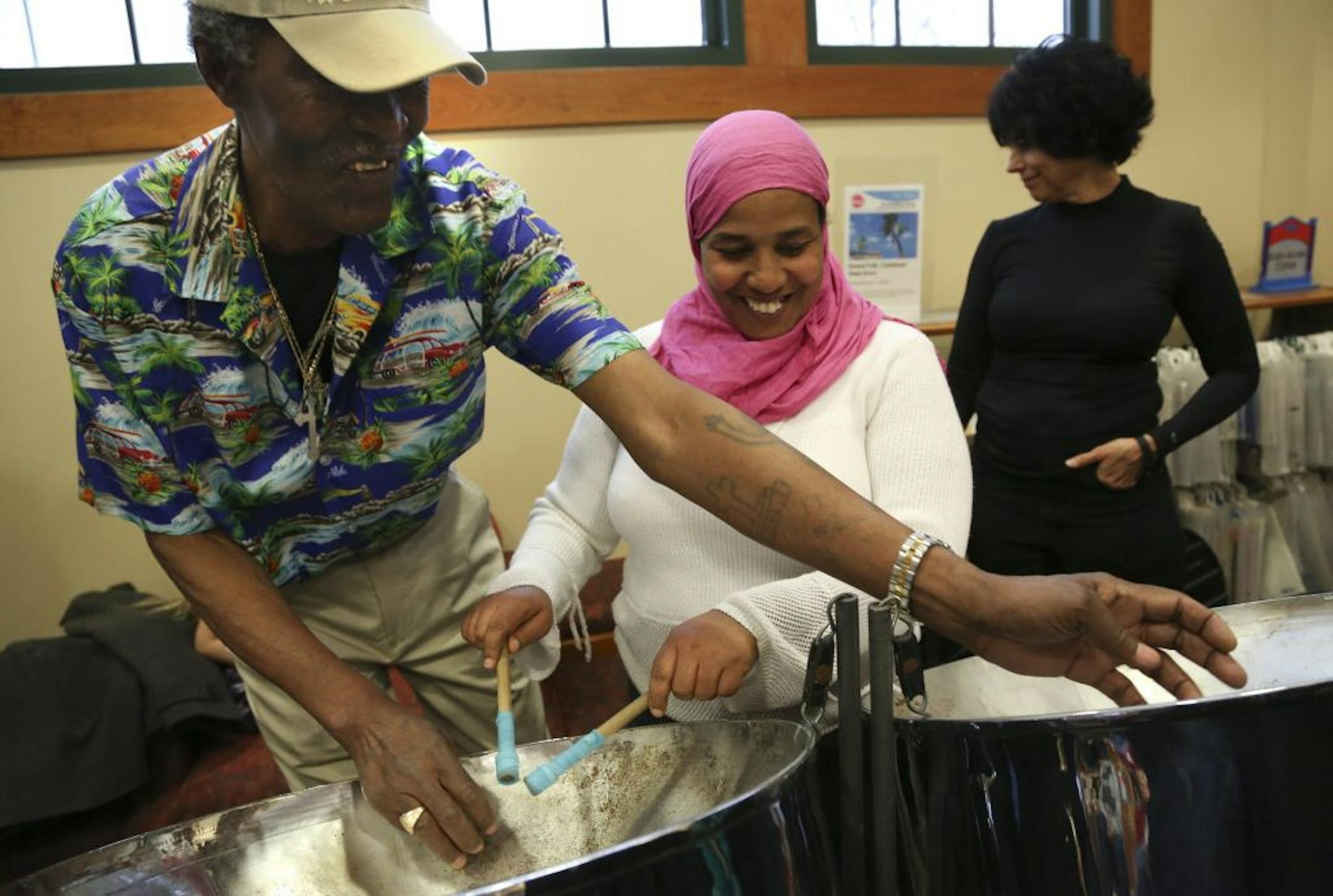 During a break from performing, Norbert Augustine showed Teseme Kuta how to play a few notes on the steel drums at the Pierre Bottineau Library in Minneapolis, Min., Friday December 1, 2012.