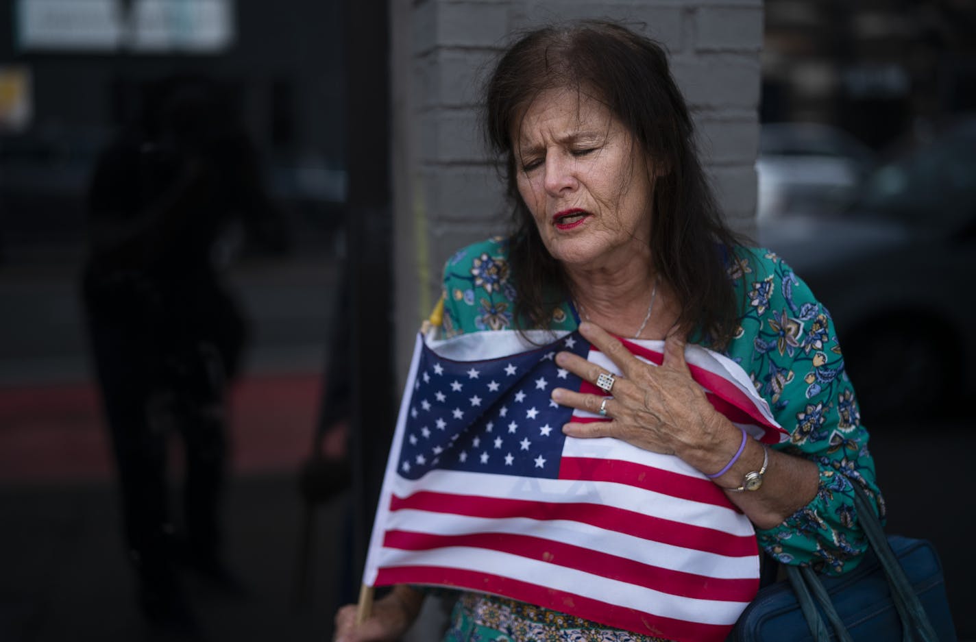 Merrilyn Downs clinched the U.S. flag as she prayed at the site where a shooting happened early Sunday Morning in the 2900 block of Hennepin Avenue south.] Jerry Holt •Jerry.Holt@startribune.com Gunmen unleashed a torrent of gunfire in a crowded Uptown block early Sunday in Minneapolis, killing one person and wounding 11 others in one of the city's most violent shootings in recent memory. Sunday ,June 21, 2020 in Minneapolis ,MN.