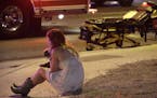 A woman sits on a curb at the scene of a shooting outside of a music festival along the Las Vegas Strip, Monday, Oct. 2, 2017, in Las Vegas. Multiple 