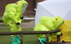 Personnel in hazmat suits work to secure a tent covering a bench in the Maltings shopping centre in Salisbury, England on Thursday March 8, 2018, wher