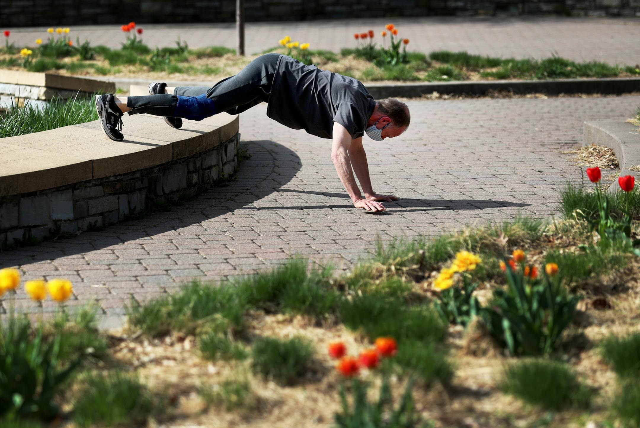 Dennis Dischinger used a ledge to exercise his upper body while working out with a group in Minnehaha Park as tulips were in full bloom Wednesday, May 6, 2020, in Minneapolis, MN.