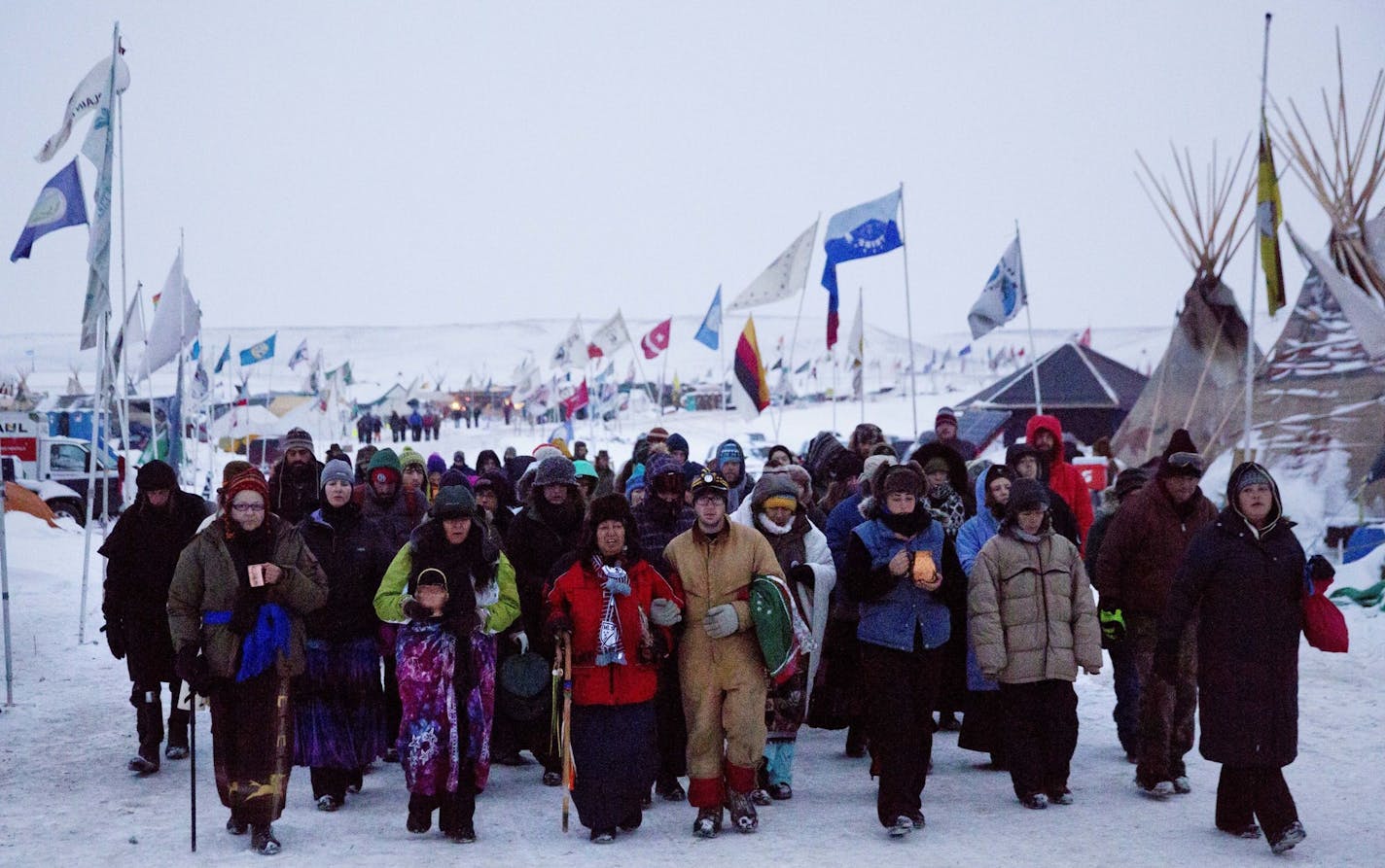 FILE - In this Thursday, Dec. 1, 2016, file photo, Beatrice Menase Kwe Jackson, center, walks with Daniel Emory, both of the Ojibwe Native American tribe as they lead a procession to the Cannonball river for a traditional water ceremony at the Oceti Sakowin camp where people have gathered to protest the Dakota Access oil pipeline in Cannon Ball, N.D. Some Native Americans worry the transition to a Donald Trump administration signals an end to eight years of sweeping Indian Country policy reforms