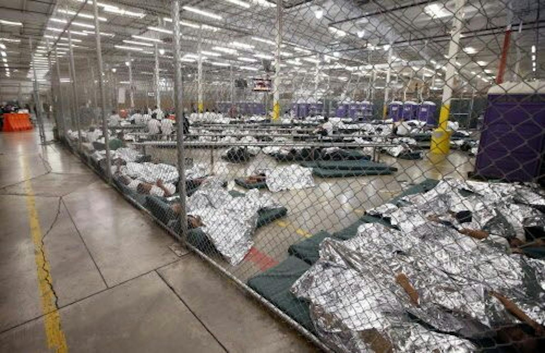 Immigrant child detainees sleep and watch television in a holding cell where hundreds of mostly Central American immigrant children are being processed and held at the U.S. Customs and Border Protection Nogales Placement Center on Wednesday, June 18, 2014, in Nogales, Ariz.