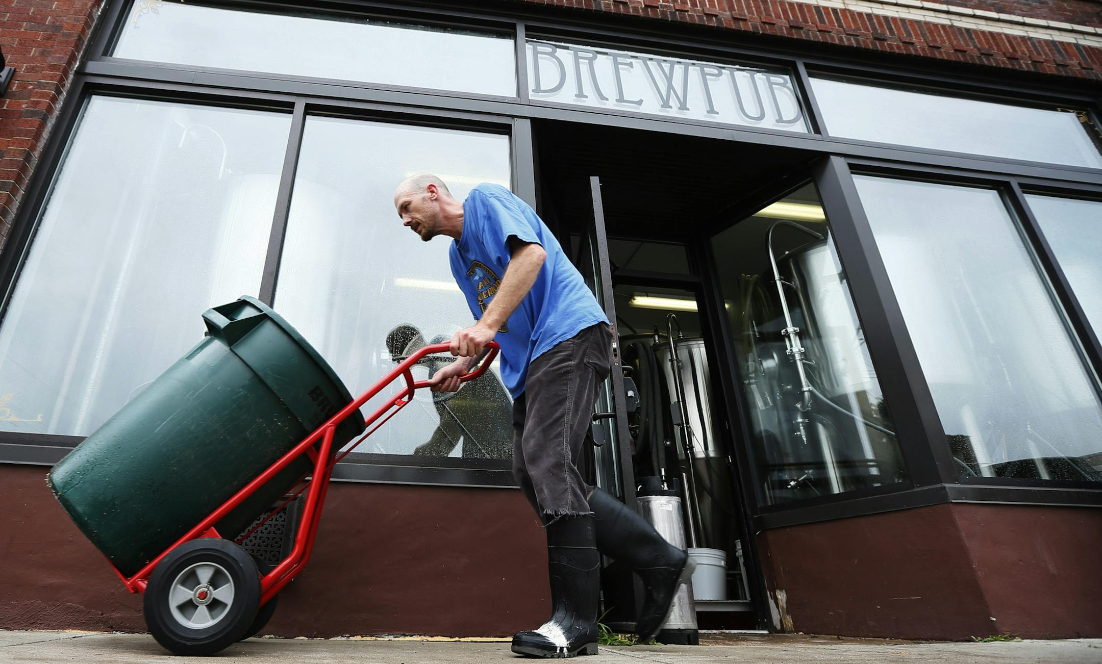 Drew Flaten an employee at Northbound Smokehouse Brewpub removed spent grain from a vat on Monday June 24 ,2013 as he brewed their first batch of beer now that power has been resorted . The Brewpub lost power in Friday's storm. and will reopen for business Tuesday morning at 11:00am ] JERRY HOLT ‚Ä¢ jerry.holt@startribune.com