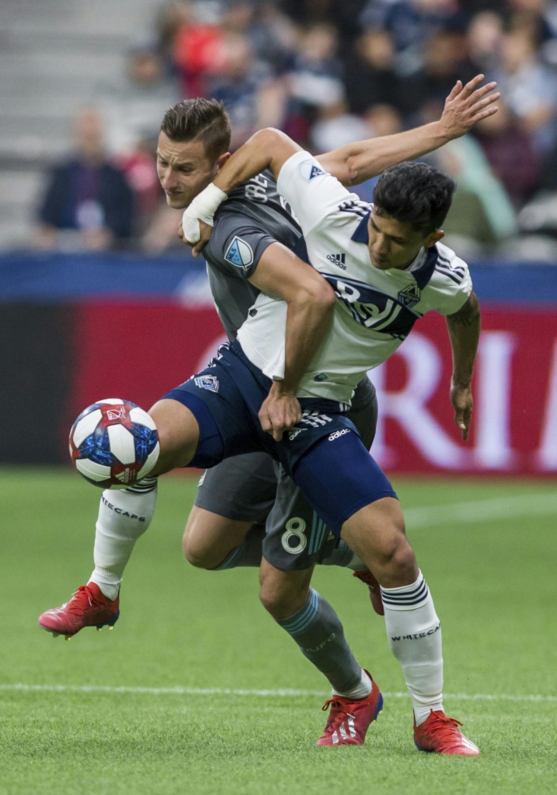Minnesota United's Jan Gregus (8) plays the ball against Vancouver Whitecaps' Fredy Montero (12) during the second half of an MLS soccer match Saturday, March 2, 2019, in Vancouver, British Columbia.
