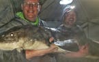Darren Troseth, 45, of Jordan, holding the sturgeon with help from his fishing buddy, John Kimble of Prior Lake, wearing the headlamp. Photo received 