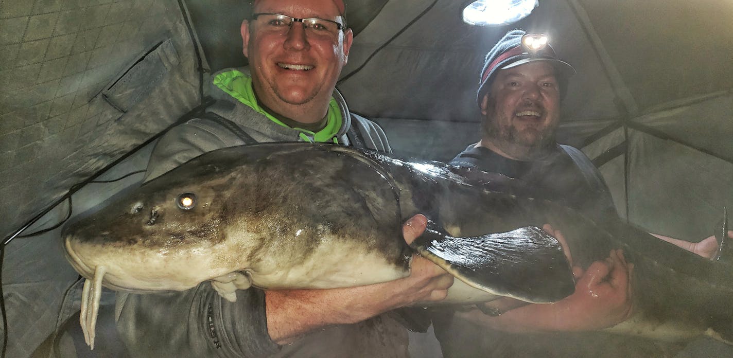 Darren Troseth, 45, of Jordan, holding the sturgeon with help from his fishing buddy, John Kimble of Prior Lake, wearing the headlamp. Photo received on Feb. 13, 2019.