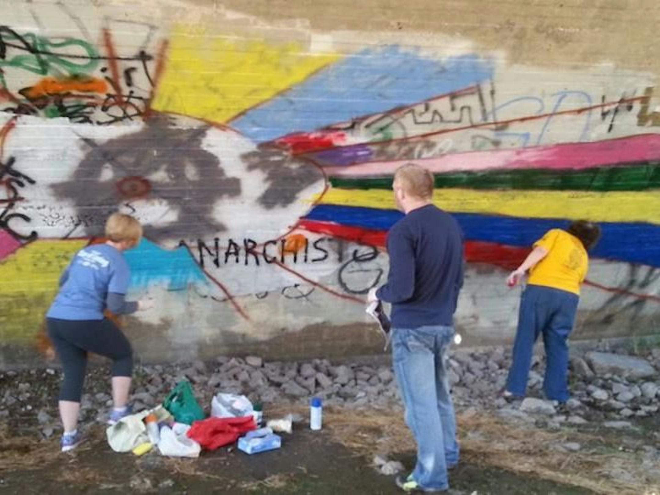 Volunteers cover graffiti under the Roosevelt Bridge in Austin with a colorful sunburst mural. Now Mower County officials want to paint over both the graffiti and the mural. ORG XMIT: F2iCz0Fp-8dzAM2nWVsg