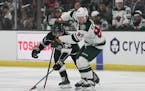 Los Angeles Kings defenseman Sean Durzi (50) and Minnesota Wild left wing Kirill Kaprizov (97) reach for the puck during the second period of an NHL h