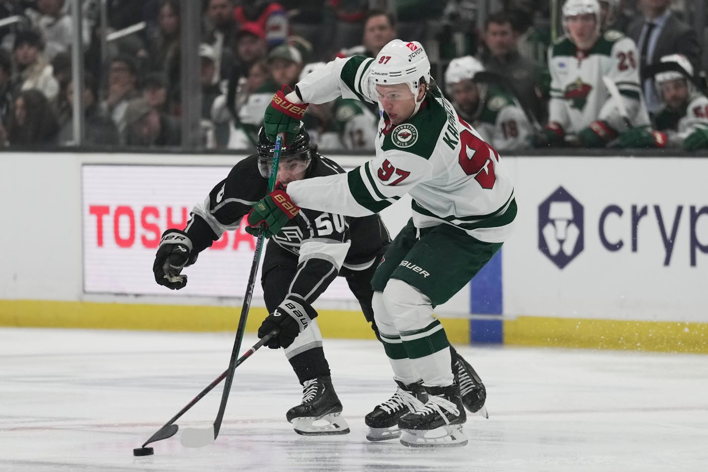 Los Angeles Kings defenseman Sean Durzi (50) and Minnesota Wild left wing Kirill Kaprizov (97) reach for the puck during the second period of an NHL hockey game Tuesday, Nov. 8, 2022, in Los Angeles. (AP Photo/Ashley Landis)