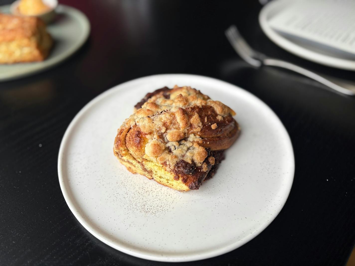 A white plate holding a square slice of chocolate braided bread.