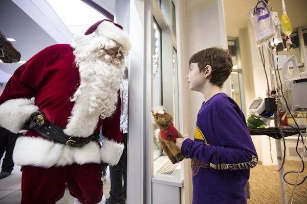 Luke Schumacher, 9, visits with Santa Claus, played by retired St. Paul police officer Tim Bradley, during a visit to patients at Children's Hospitals