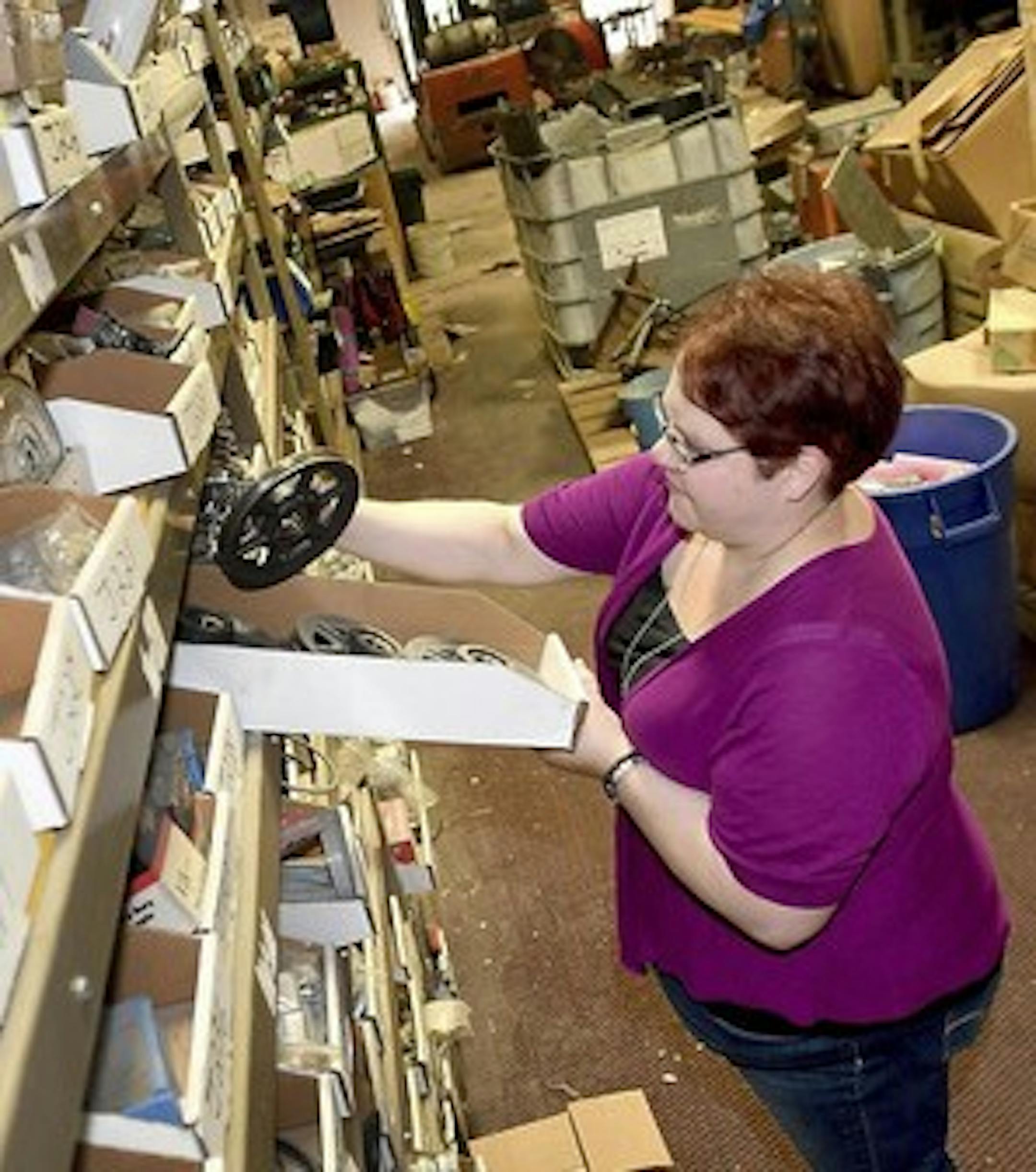 Kimberly Salisbury goes through some of the stock on hand at NPS Industrial Surplus in Nicollet, Minn. She and her husband Jason run the online auction business out of a warehouse near their home. (Pat Christman/The Free Press via AP)