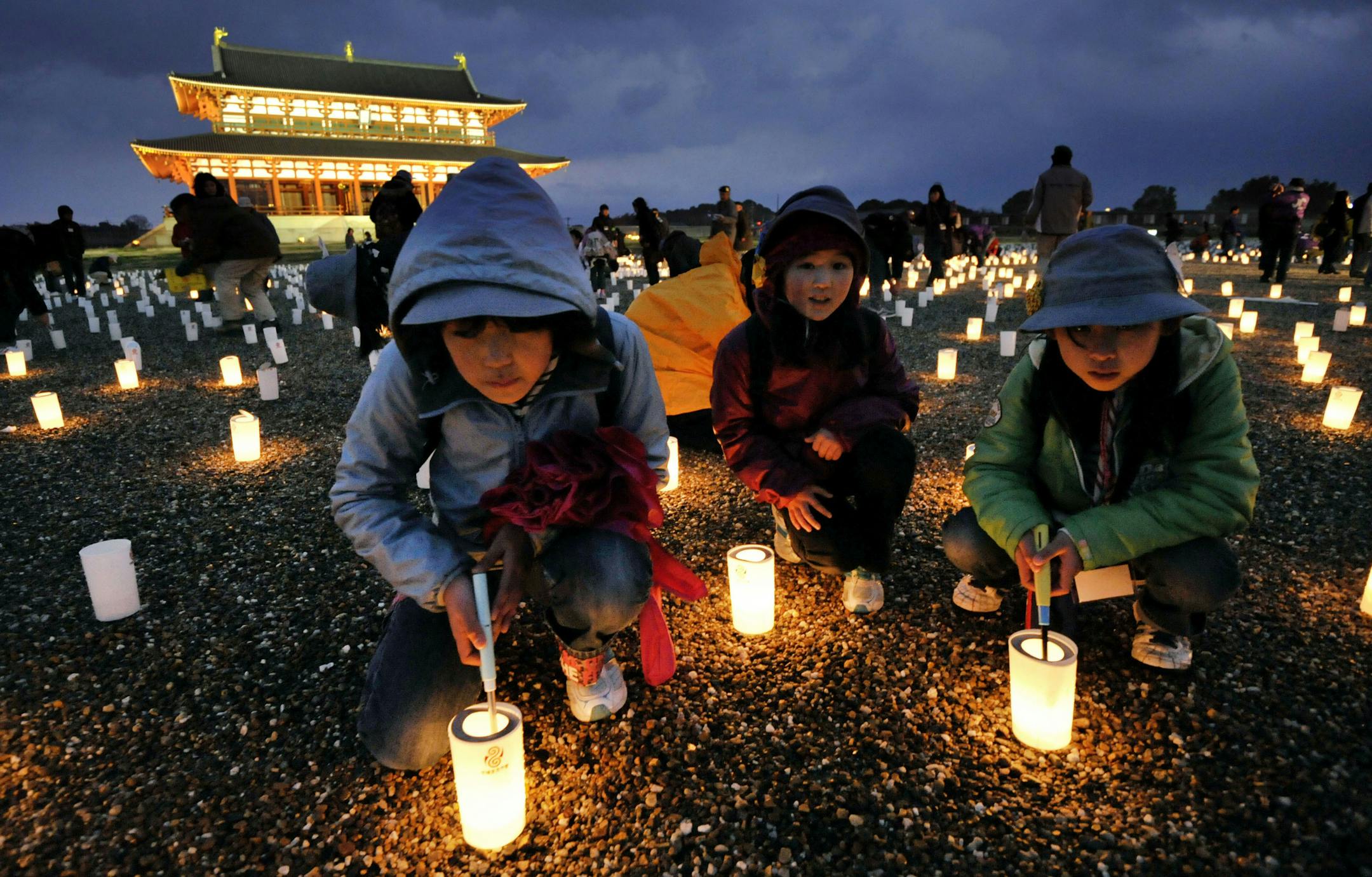 Children light candles during a memorial service for the victims of the March 11, 2011 earthquake and tsunami, near the site of Heijo Palace in Nara, central Japan, Sunday, March 11, 2012. Japan on Sunday was remembering the massive earthquake and tsunami that struck the nation a year ago, killing just over 19,000 people and unleashing the world's worst nuclear crisis in a quarter century. (AP Photo/Kyodo News) JAPAN OUT, MANDATORY CREDIT, NO LICENSING IN CHINA, HONG KONG, JAPAN, SOUTH KOREA AND