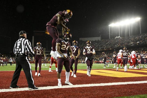 Teammates, including Gophers wide receiver Tyler Johnson (6), celebrated with running back Mohamed Ibrahim (24) after he scored a second half touchdow