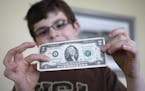 In this April 13, 2010 photo, Tucker Parrish, 8 looks over a two dollar bill while his brothers work on their coin collections in West Linn, Ore. (AP 