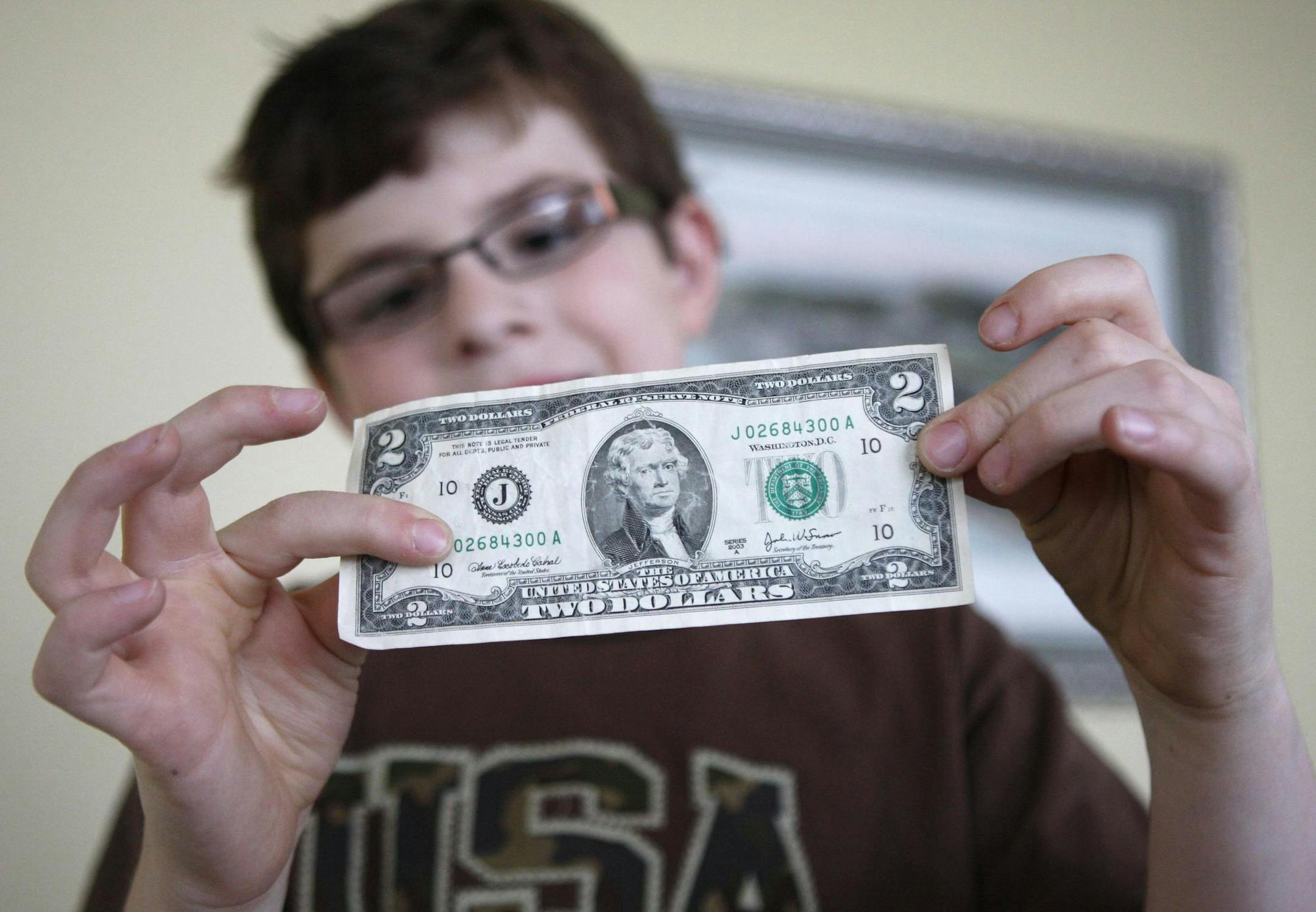 In this April 13, 2010 photo, Tucker Parrish, 8 looks over a two dollar bill while his brothers work on their coin collections in West Linn, Ore. (AP Photo/Rick Bowmer)