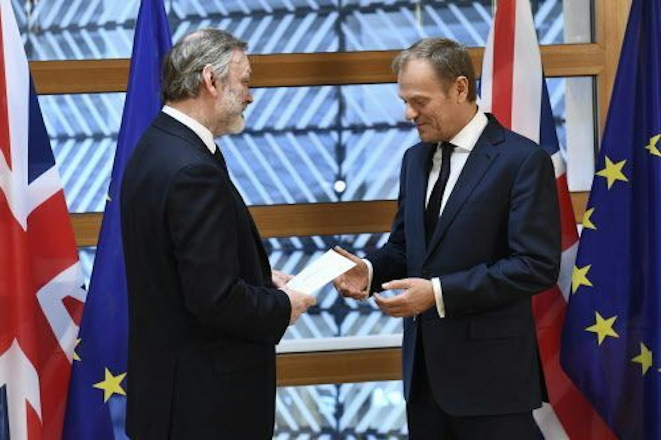 EU Council President Donald Tusk, right, gets British Prime Minister Theresa May's formal notice to leave the bloc under Article 50 of the EU's Lisbon Treaty from UK Permanent Representative to the EU Tim Barrow in Brussels, Wednesday, March 29, 2017. Barrow hand-delivered the letter signed by Britain's Prime Minister Theresa May that will formally trigger the beginning of Britain's exit from the European Union.