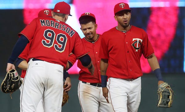 Minnesota Twins' Eduardo Escobar, center, Eddie Rosario, right, and others celebrate the team's 7-4 over the Cleveland Indians