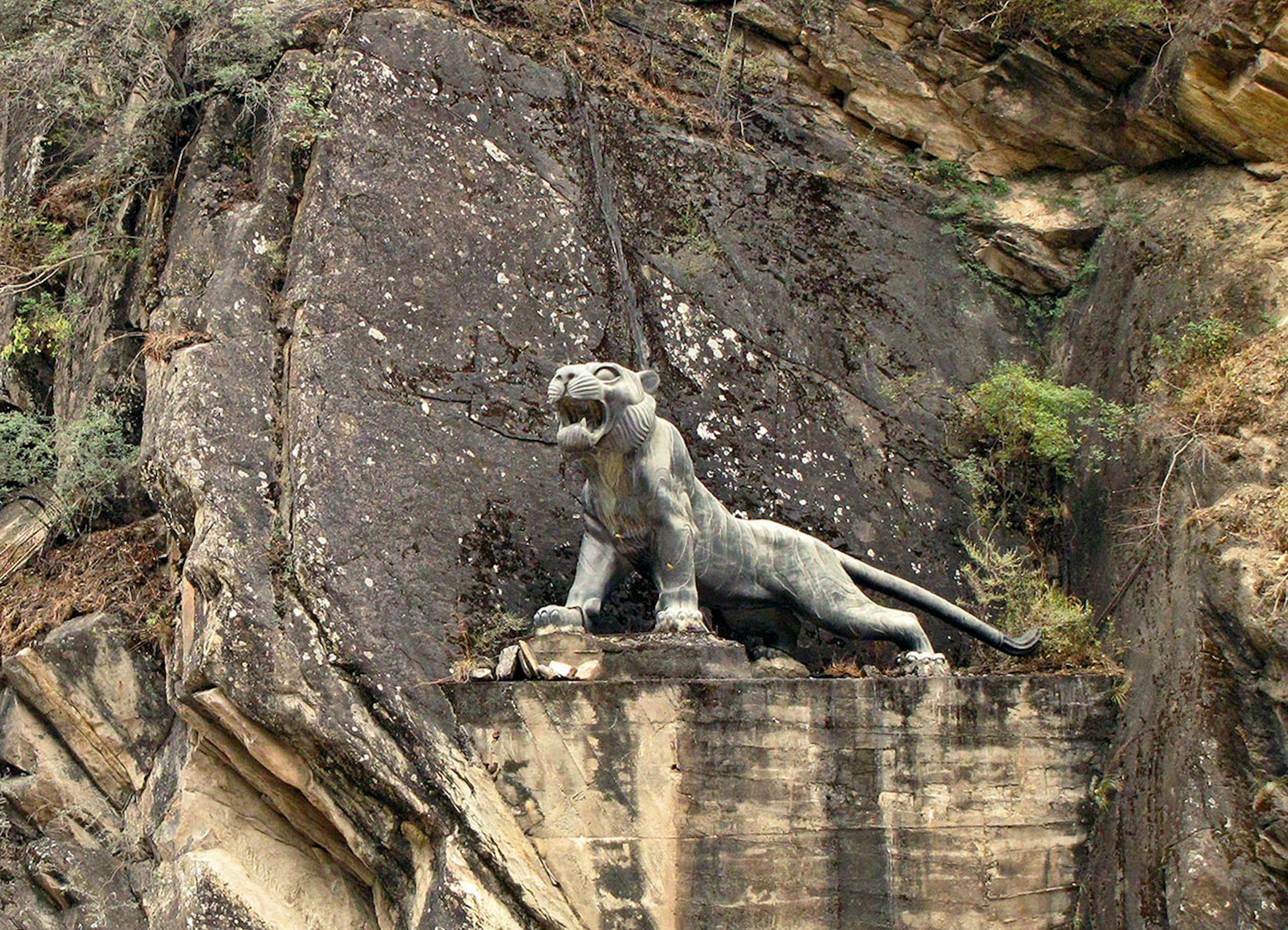 At the visitor service center, a snarling stone tiger is perched on a ledge across the rushing Jinsha River.
