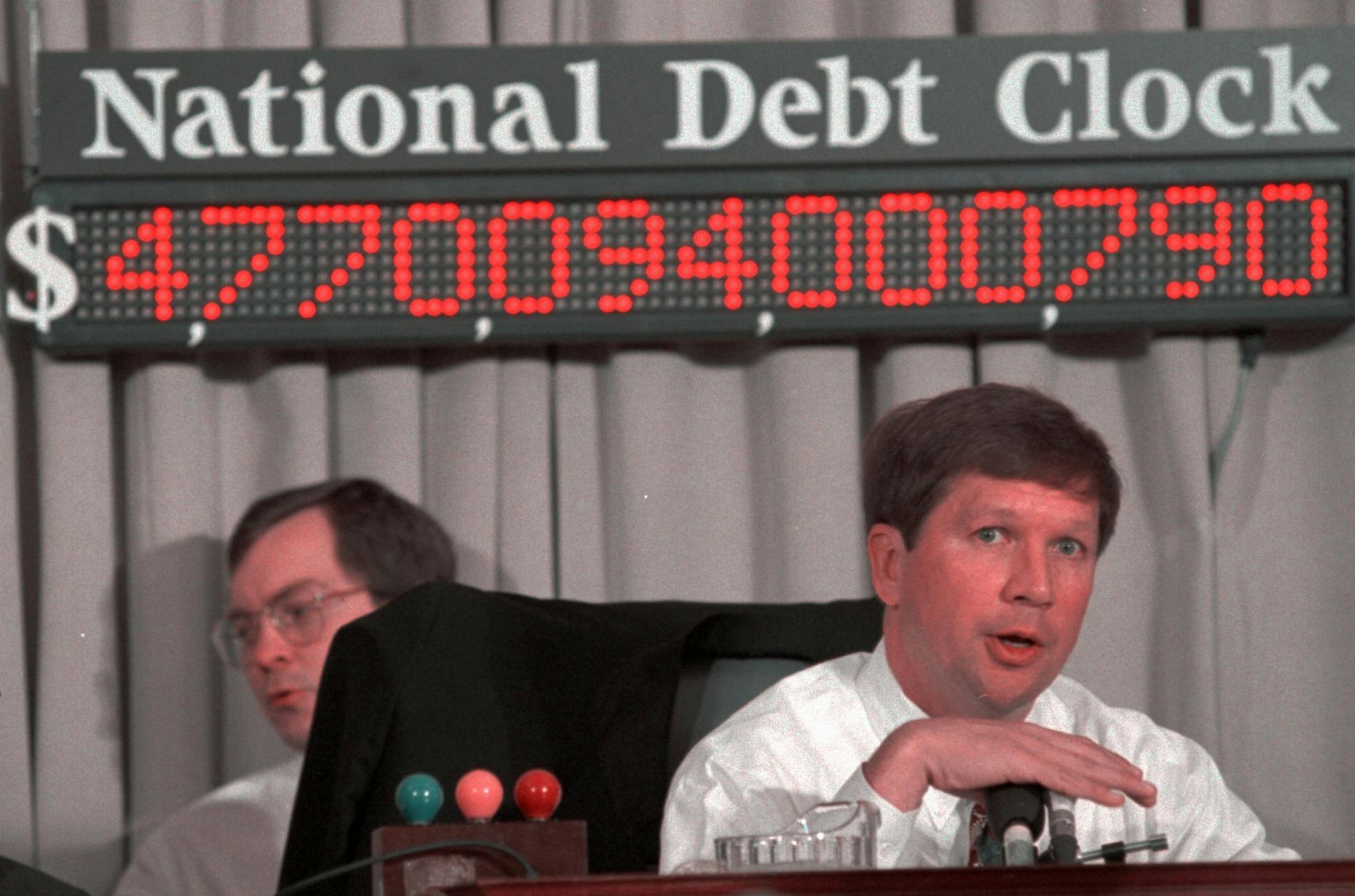 House Budget Committee Chairman Rep. John Kasich, R-Ohio, sits in front of the National Debt Clock during a hearing of the committee on Capitol Hill Wednesday May 10, 1995. With Democrats attacking them at every turn, Republicans Wednesday began pushingbalanced-budget plans through Congress, looking for huge savings from Medicare and Medicaid and elimination of scores of federal programs. (AP Photo/Marcy Nighswander)