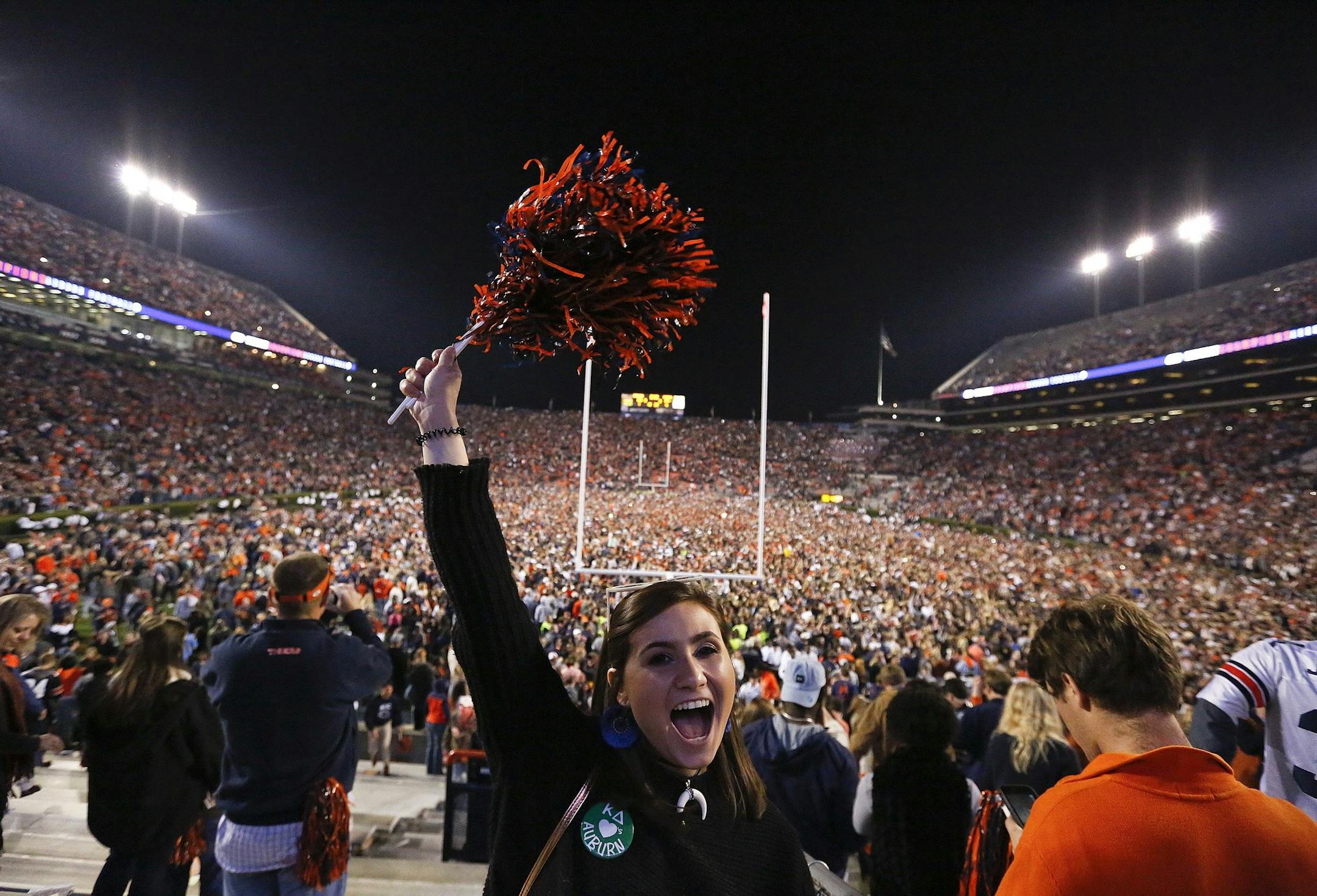 A fan cheers as the crowd rushes the field after Auburn won 26-14 in the Iron Bowl NCAA college football game against Alabama, Saturday, Nov. 25, 2017, in Auburn, Ala. (AP Photo/Brynn Anderson)