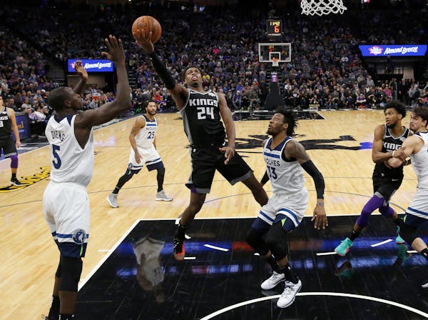Kings guard Buddy Hield goes to the basket between the Timberwolves' Gorgui Dieng (5) and Robert Covington (33) during the second half