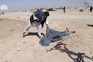 FILE -- In this Monday, Oct. 10, 2016 file photo, an Afghan man looks at the body of a victim of suicide attack blamed on the Taliban, in Lashkar Gah,