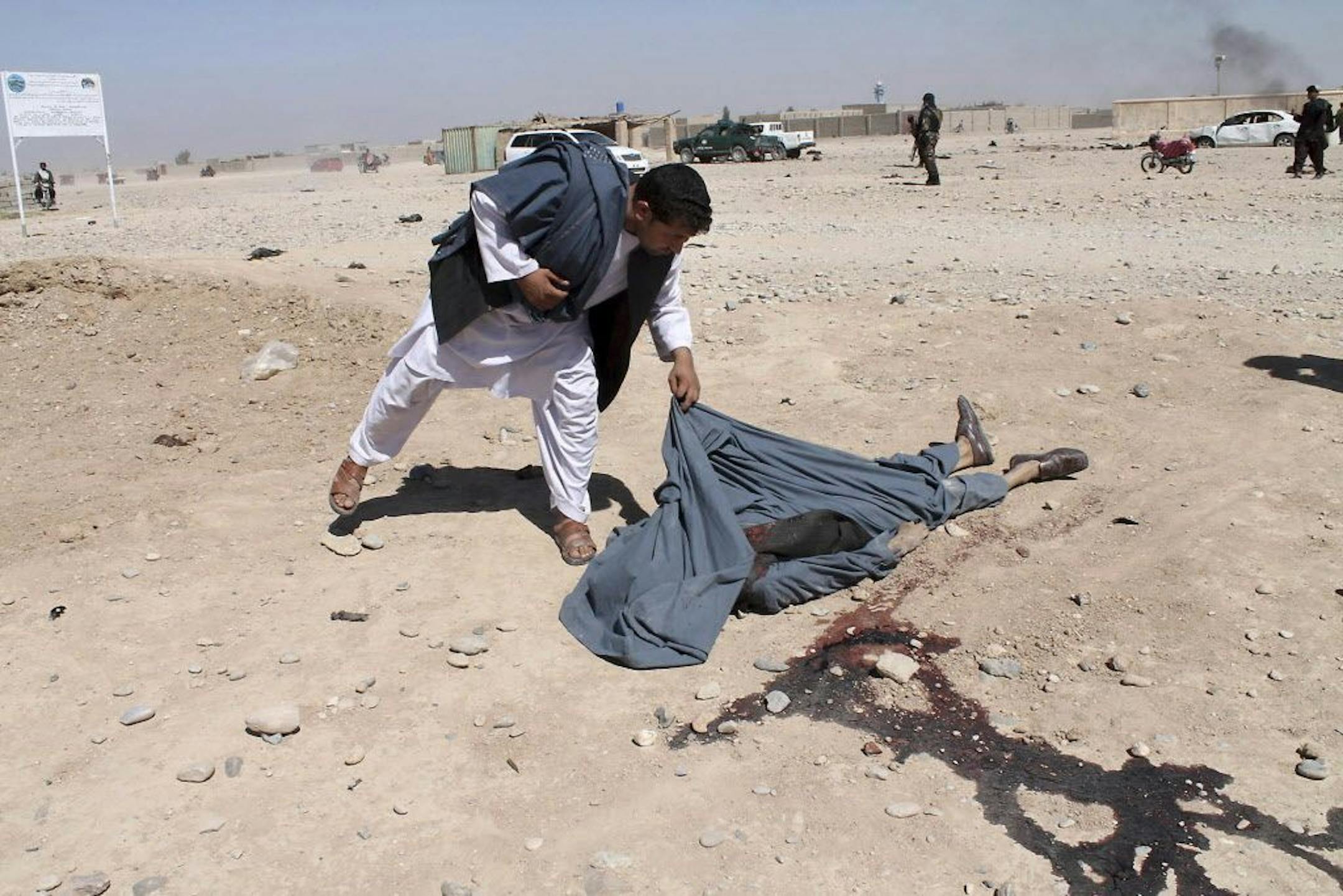 FILE -- In this Monday, Oct. 10, 2016 file photo, an Afghan man looks at the body of a victim of suicide attack blamed on the Taliban, in Lashkar Gah, Helmand province, Afghanistan. For the past month, the Taliban have held control over most of Afghanistan�s Helmand province, where the majority of the world�s opium is grown -- and as insurgent attacks intensify around the provincial capital, residents are blaming rampant government corruption for the rising militant threat. At an international a