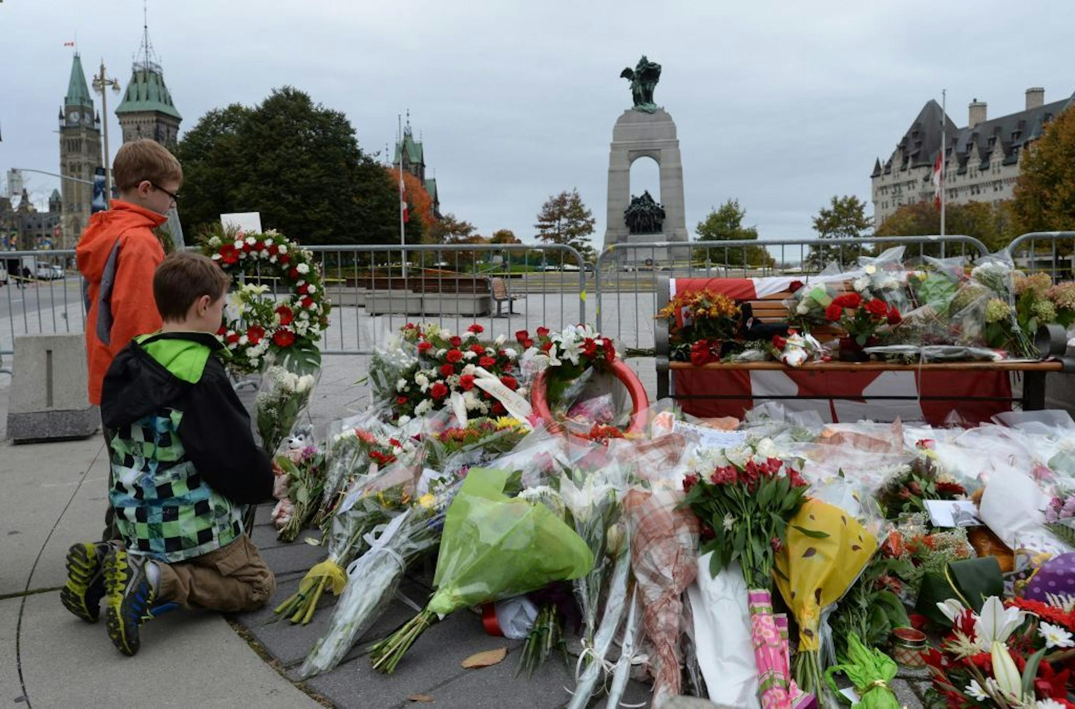 Two boys lay floral tributes for Cpl. Nathan Cirillo at the National War Memorial in Ottawa on Thursday, Oct. 23, 2014. Canadians are mourning the loss of Cpl. Nathan Cirillo, the army reservist who was shot dead as he stood guard before the Tomb of the Unknown soldier on Wednesday. Flags were flown at half-staff to honor Cirillo, a 24-year-old a reservist from Hamilton, Ontario, whose shooting on Wednesday began an attack that ended with a lone gunman storming into Parliament and opening fire b