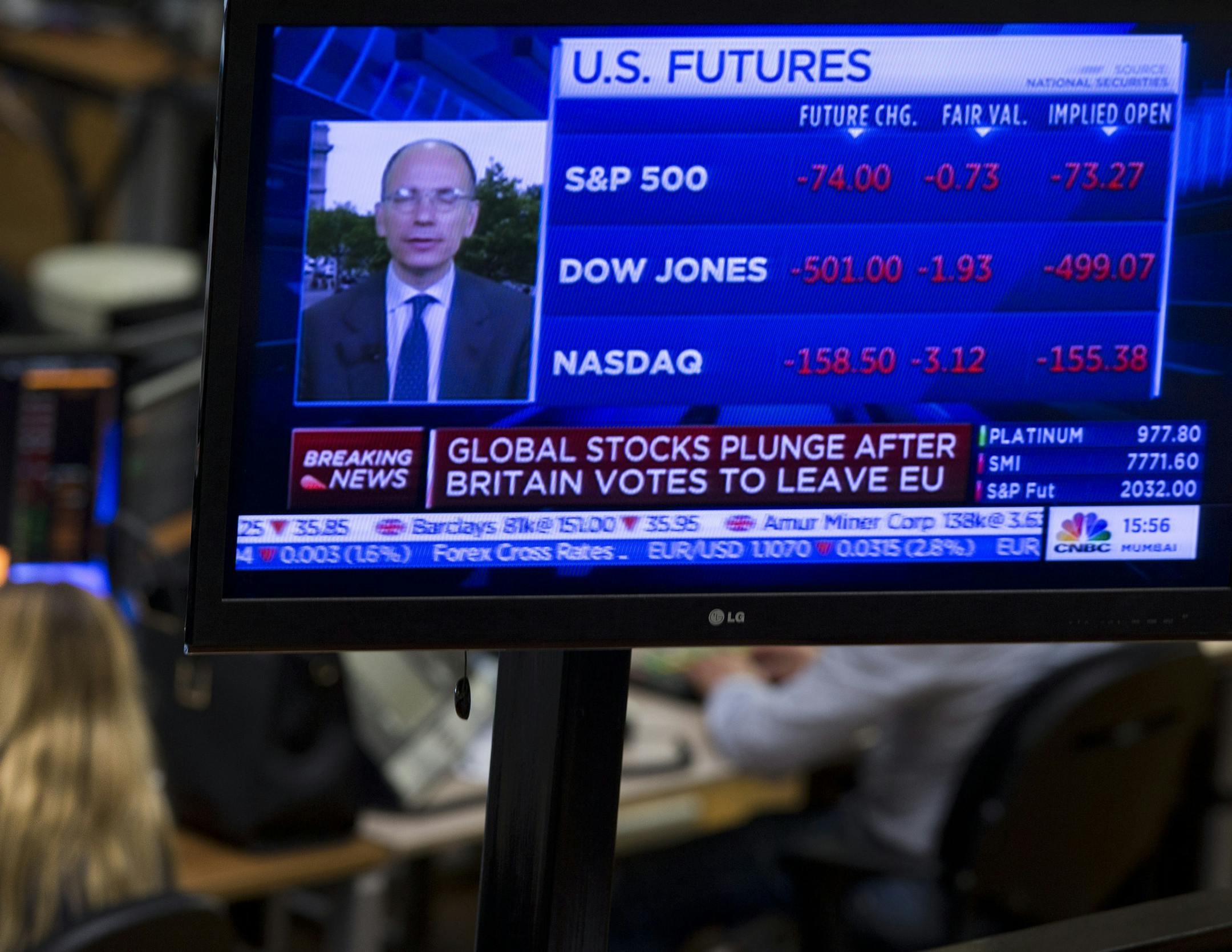 A TV screen shows global stocks plunging following the British Brexit vote as traders, background, work at the Euronext Amsterdam Stock Exchange, Netherlands, Friday, June 24, 2016. The British vote to leave the EU shook up financial markets around the globe on Monday, leading to sharp falls in stocks and the British pound.(AP Photo/Peter Dejong)