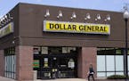 FILE - In this Wednesday, May 18, 2016, file photo, a woman walks past a Dollar General store in Methuen, Mass. On Thursday, Aug. 25, 2016, Dollar Gen