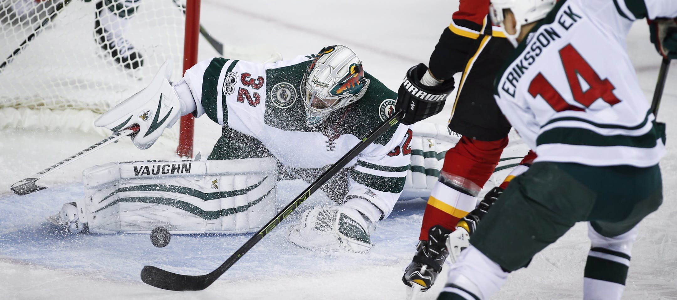 Minnesota Wild goalie Alex Stalock, left, stops Calgary Flames' Michael Frolik, center, from the Czech Republic, as the Wild's Joel Eriksson, from Sweden, watches during the first period of an NHL hockey game Saturday, Oct. 21, 2017, in Calgary, Alberta. (Jeff McIntosh/The Canadian Press via AP)