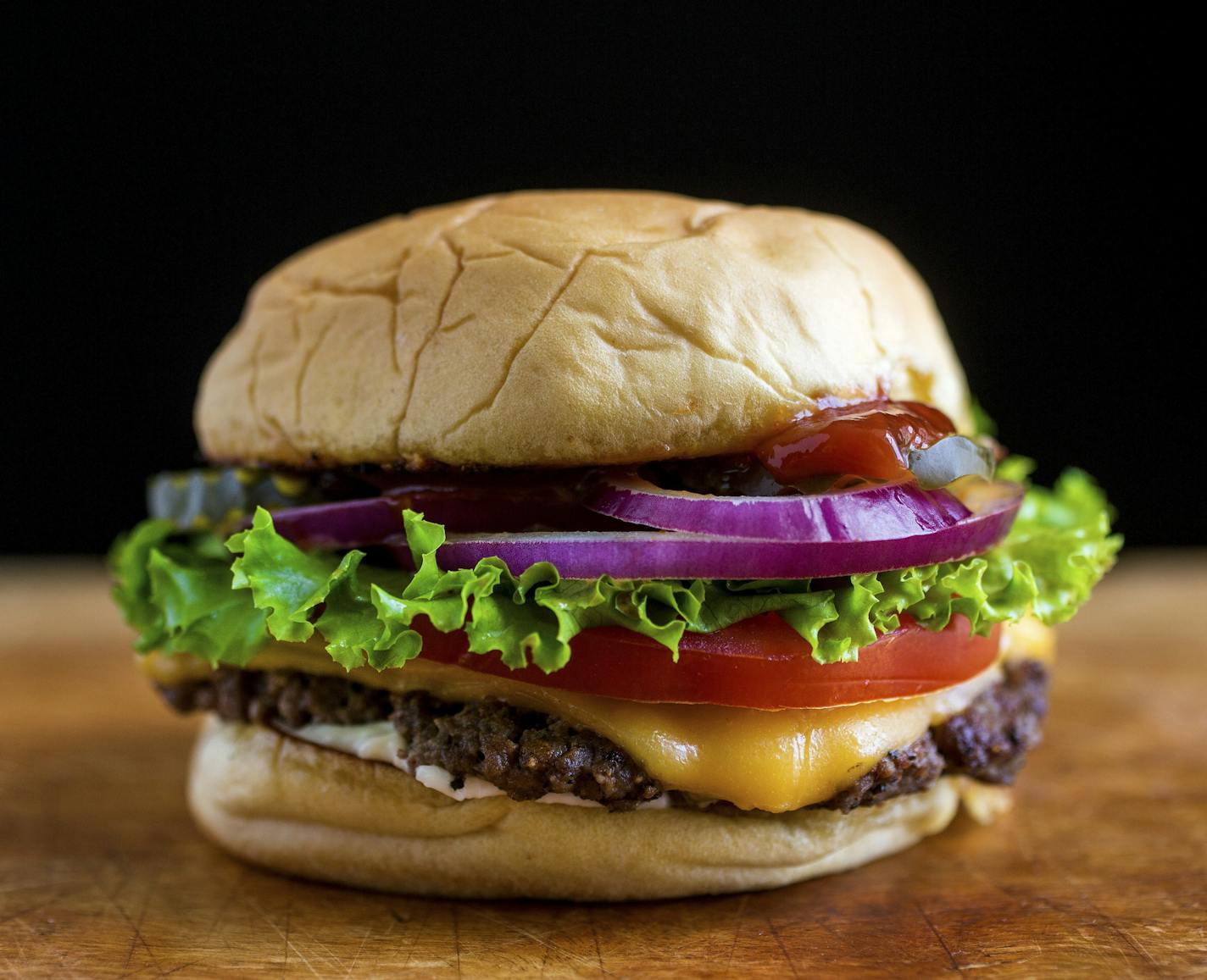 A diner-style burger, smashed thin and cooked crisp on its edges, in New York, June 2014. The secret to cooking a great hamburger is simple, experts say: Cook on heavy, cast-iron pans and griddles, use an 80-20 ratio of meat to fat, use a soft bun and don't overdress. (Andrew Scrivani/The New York Times)