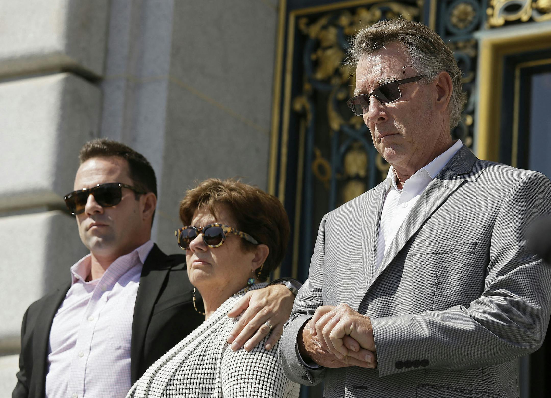 File - In this Sept. 1, 2015 file photo, from left, Brad Steinle, Liz Sullivan and Jim Steinle, the brother, mother and father of Kate Steinle who was shot to death on a pier, listen to their attorneys speak during a news conference on the steps of City Hall in San Francisco. The parents of a woman killed on a San Francisco pier by a man in the country illegally is suing the city and two federal agencies that they say contributed to her death. Kate Steinle's parents filed the wrongful-death laws