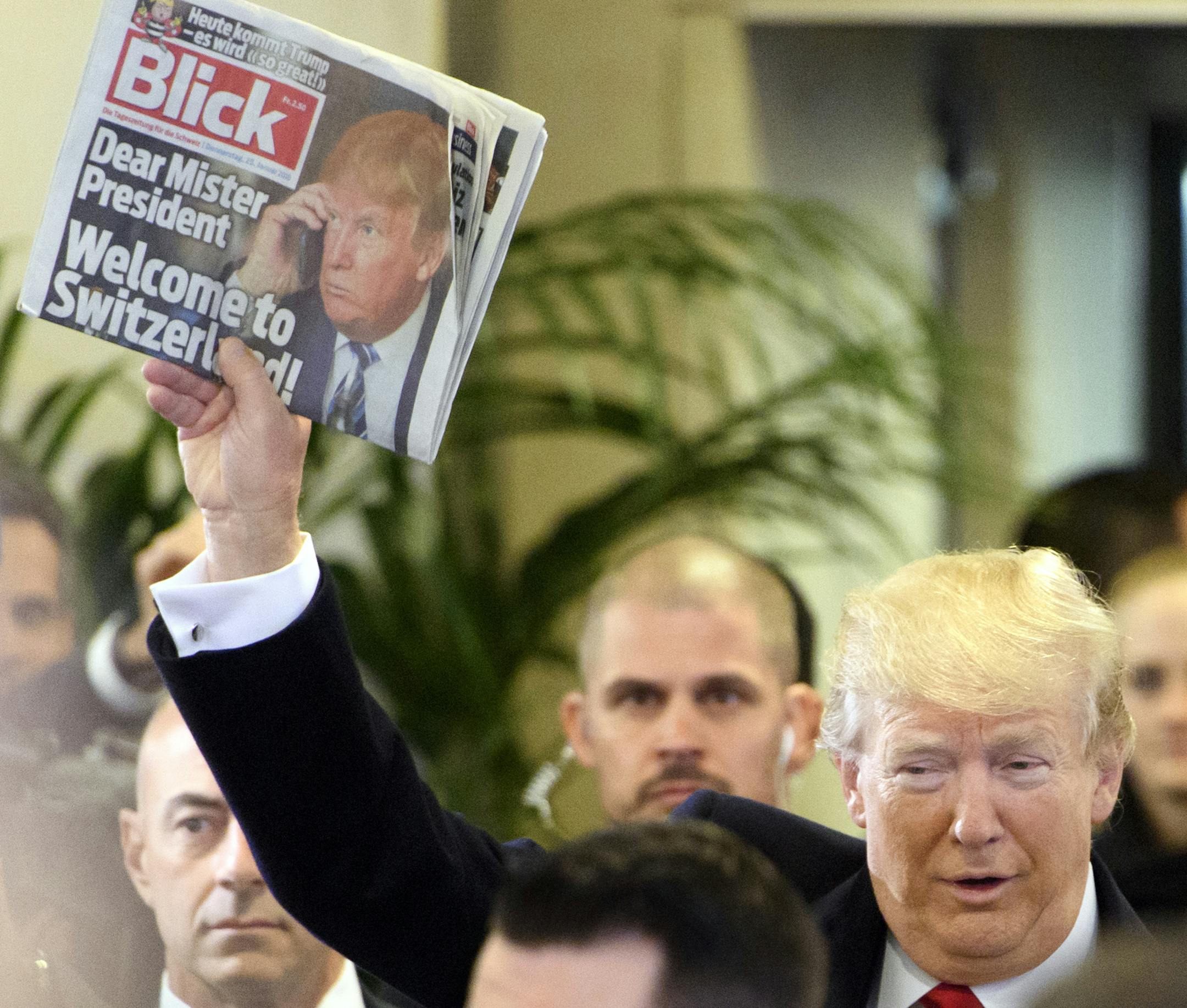 US President Donald Trump holds up Swiss newspaper 'Blick' as he arrives at the Congress Center on the last day of the annual meeting of the World Economic Forum, WEF, in Davos, Switzerland, Friday, Jan. 26, 2018. (Laurent Gillieron/Keystone via AP)