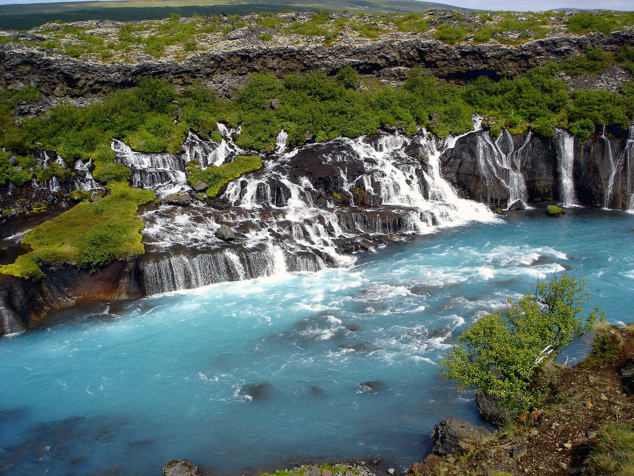 The Ring Road traces Iceland's landscape of tundra, desert, volcanic rock, glaciers and falls like Hraunfoss, where the water emerges over a lava field.