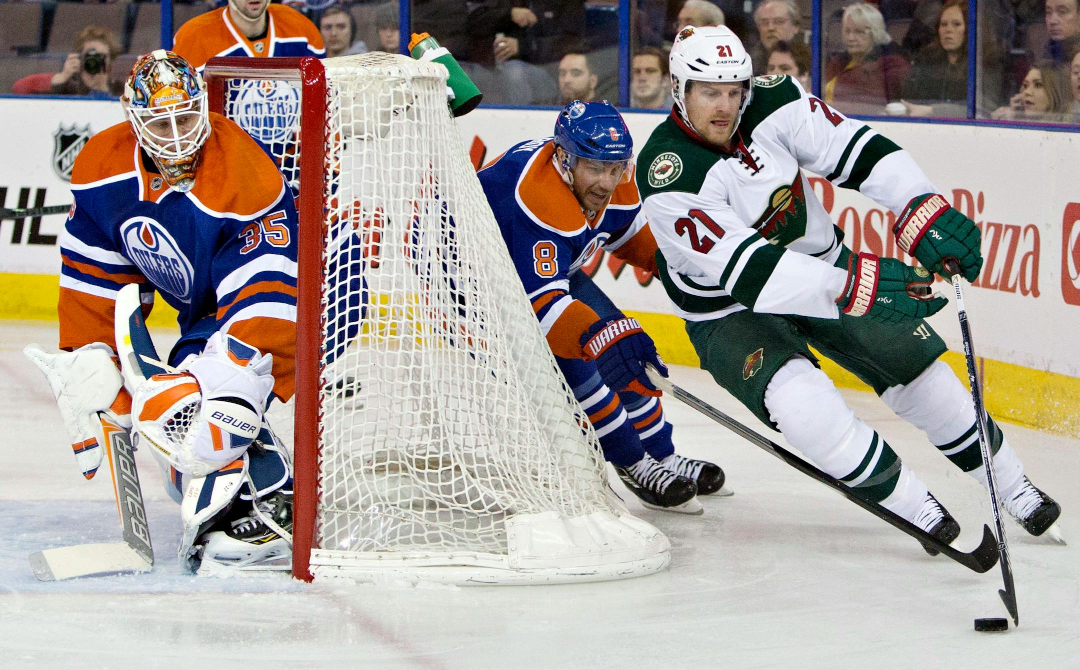 Minnesota Wild's Kyle Brodziak (21) controls the puck as Edmonton Oilers' Derek Roy (8) chases and goalie Viktor Fasth (35) looks for the shot during first period NHL hockey action in Edmonton, Alberta, on Tuesday Jan. 27, 2015. (AP Photo/The Canadian Press, Jason Franson)