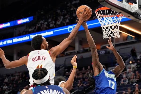 Cleveland Cavaliers forward Evan Mobley, left, blocks a shot by Minnesota Timberwolves forward Taurean Prince during the first half of an NBA basketba
