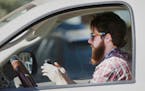 In this Feb. 26, 2013 file photo, a man uses his cell phone as he drives through traffic in Dallas.