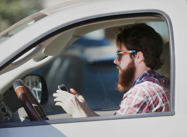 In this Feb. 26, 2013 file photo, a man uses his cell phone as he drives through traffic in Dallas.
