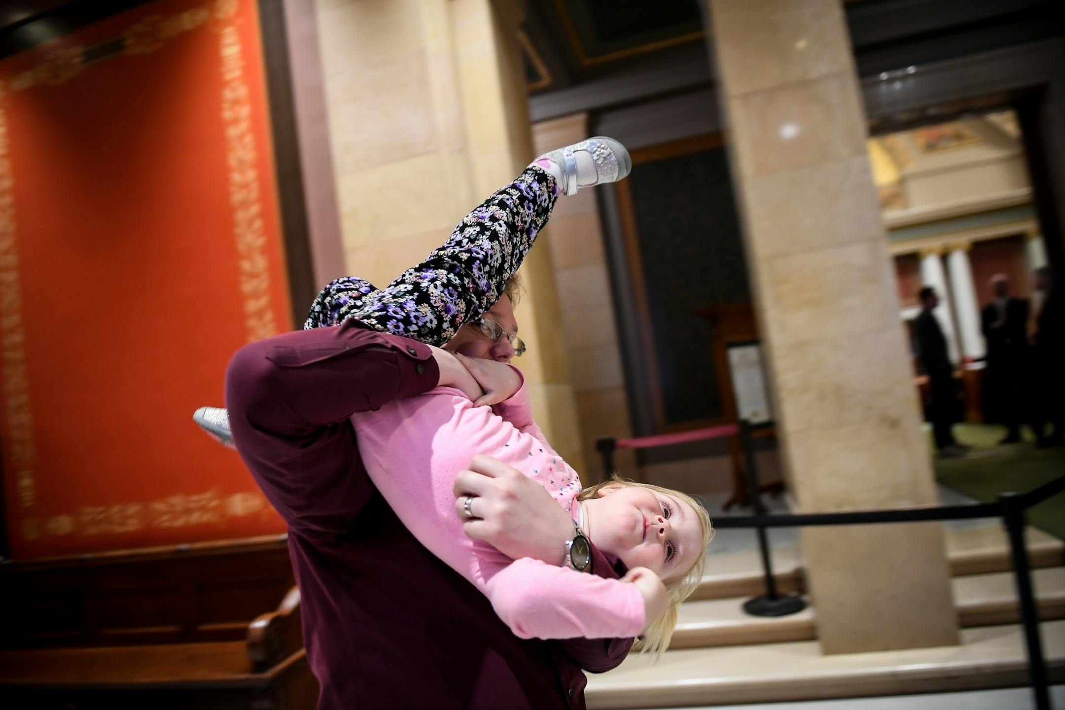 Charles Jaeger, with the Minnesota Association of Professional Employees, flipped his daughter Victoria, 2, upside-down outside the house chamber Tuesday night. Jaeger was with a group of state employees who are worried that parental leave could be inserted into a bill that could face a veto by the governor.