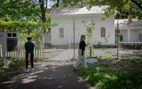 Park visitors take a look outside the fenced-in John H. Stevens House, which is under construction, in May 2025.