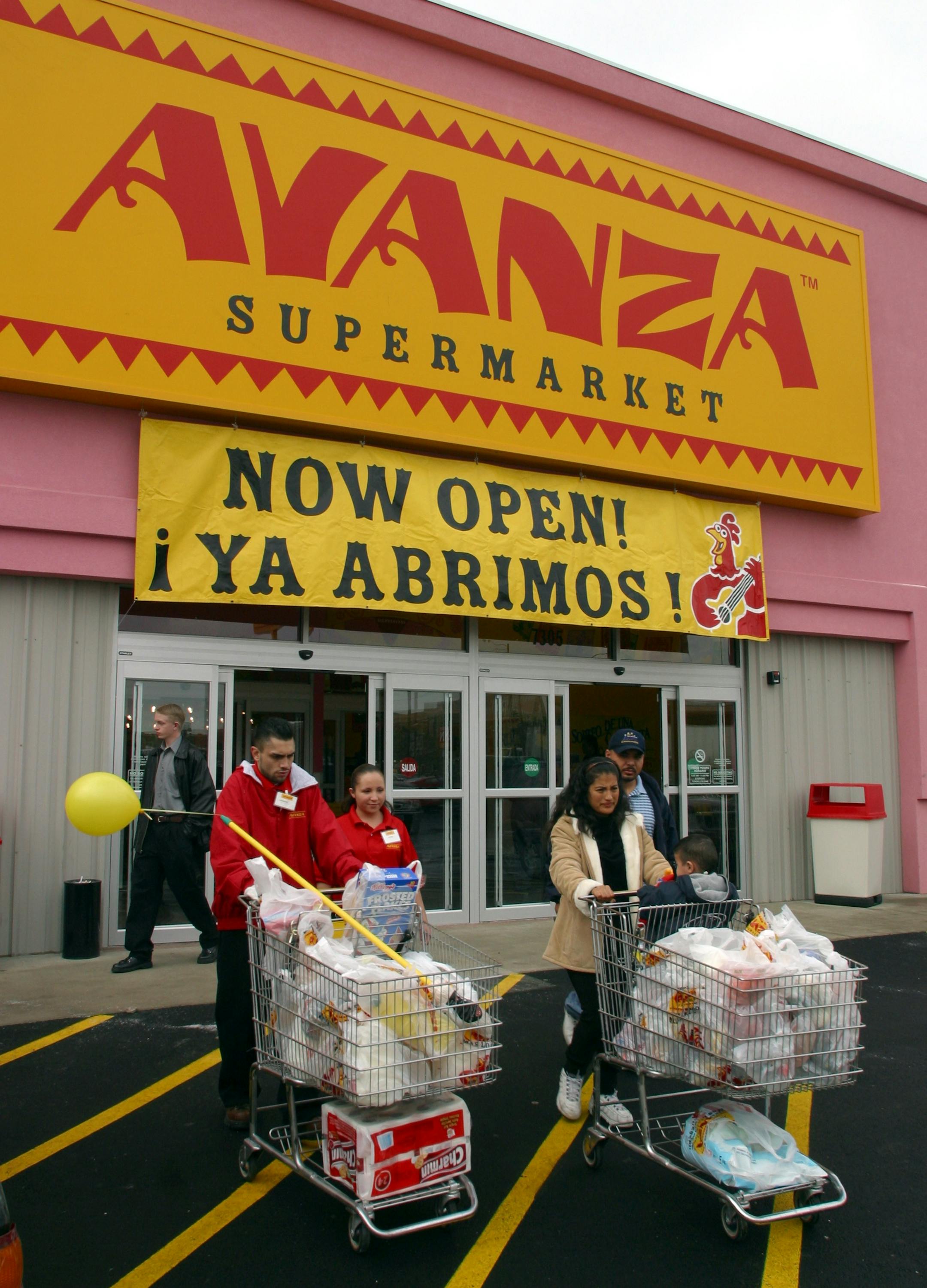 James Casias, left, an employee at the colorful new Avanza Supermarket at 73rd and Pecos, helps Leticia and Alfredo Moreno and their son Alfredo, Jr., 17 months old, right, wheel groceries to their car after the opening of the new store Wednesday morning, 2/5/03.