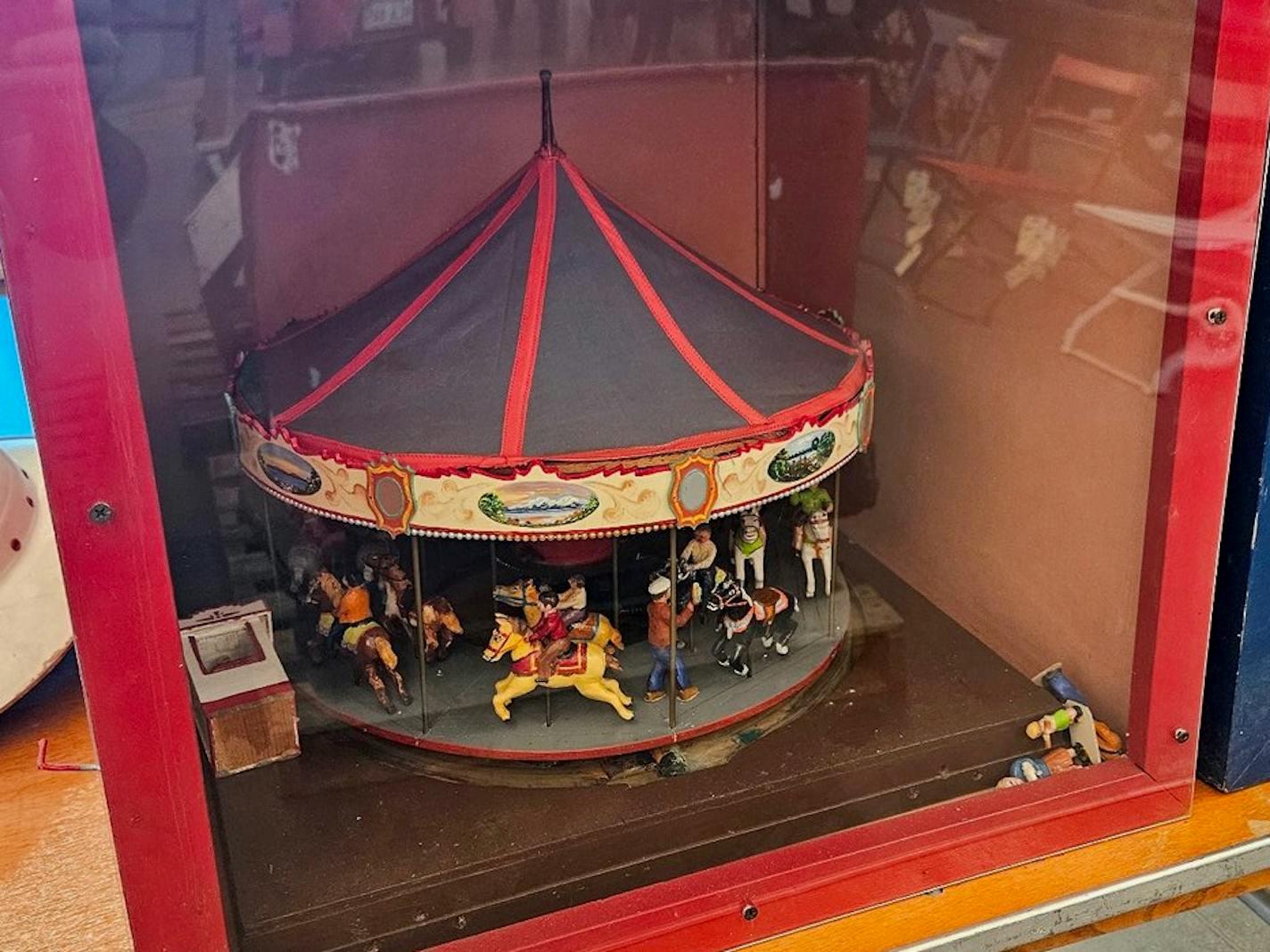 A miniature carousel inside of a glass-paned box.
