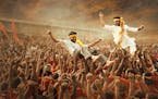 Rama (Ram Charan) and Bheem (N.T. Rama Rao Jr.) are hoisted in triumph in a scene from “RRR.” 