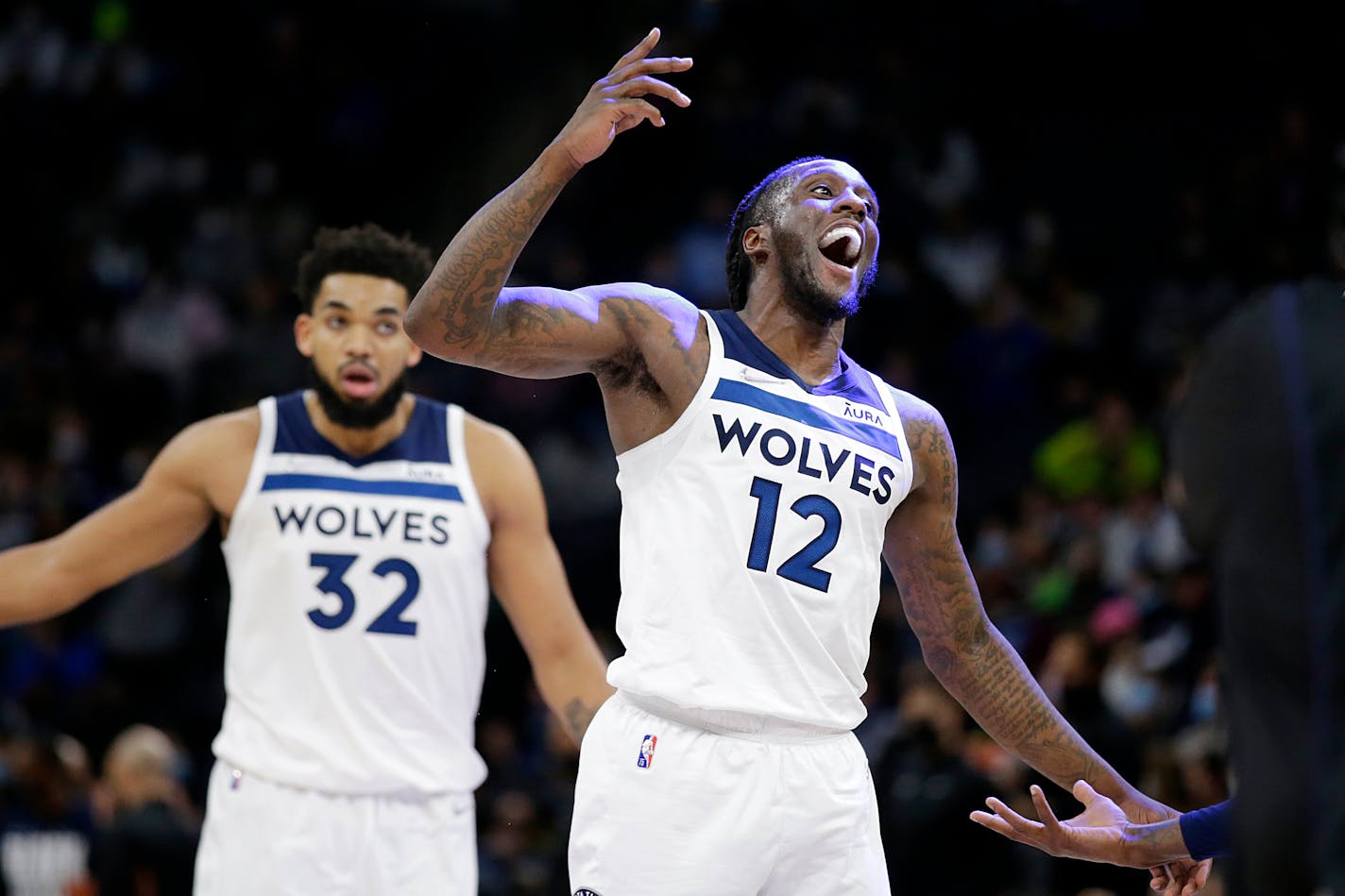 Minnesota Timberwolves forward Taurean Prince (12) celebrates as center Karl-Anthony Towns (32) watches during the second half of the team's NBA basketball game the Denver Nuggets on Tuesday, Feb. 1, 2022, in Minneapolis. (AP Photo/Andy Clayton-King)